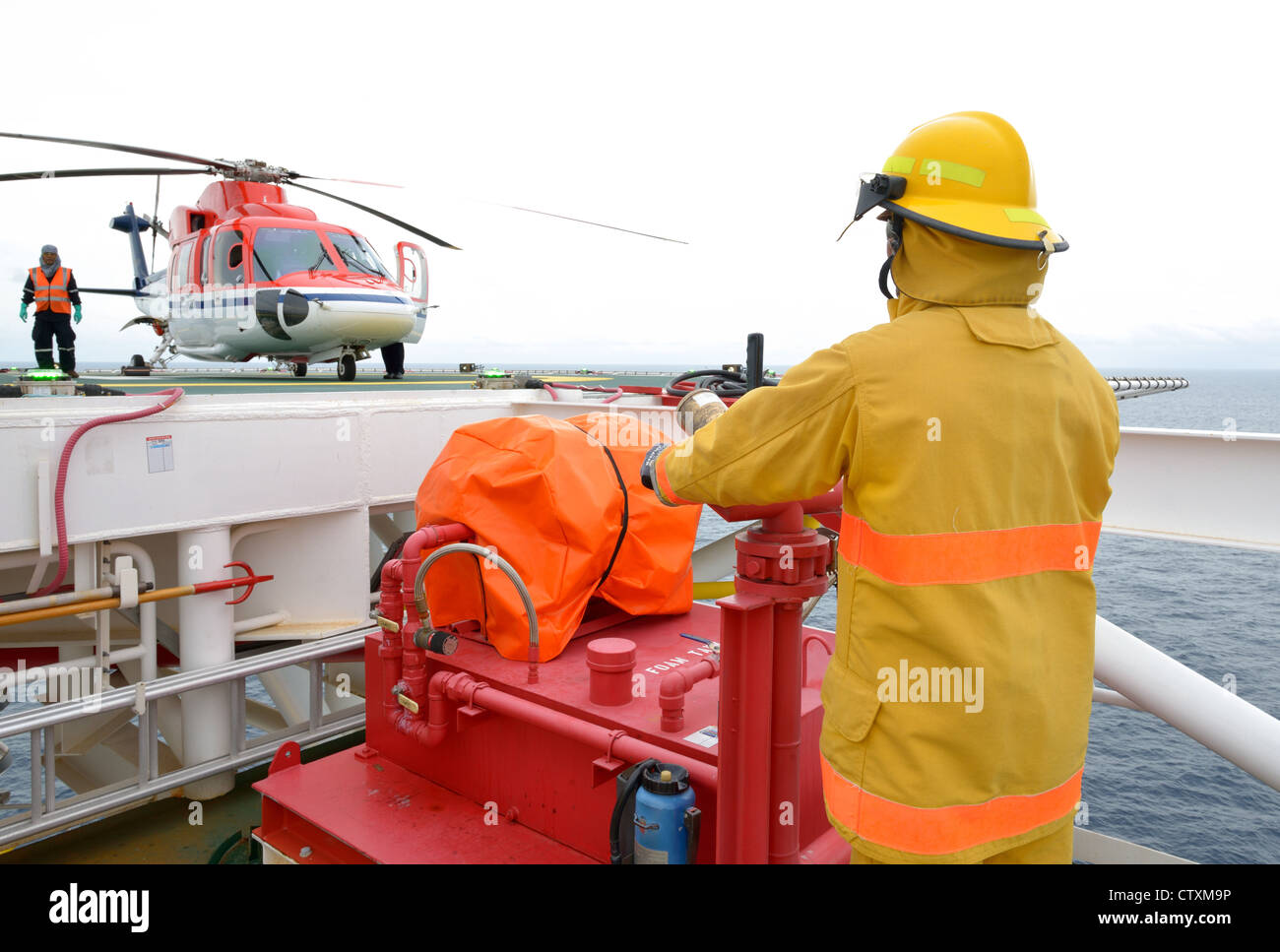 Vigile del fuoco è di guardia per elicottero offshore prima di avviare il motore. Foto Stock