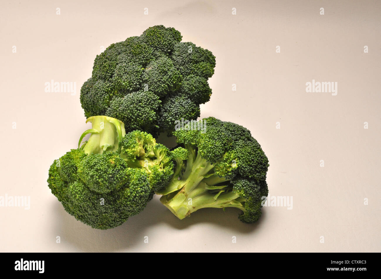 Teste di broccoli a sedersi su uno sfondo semplice Foto Stock