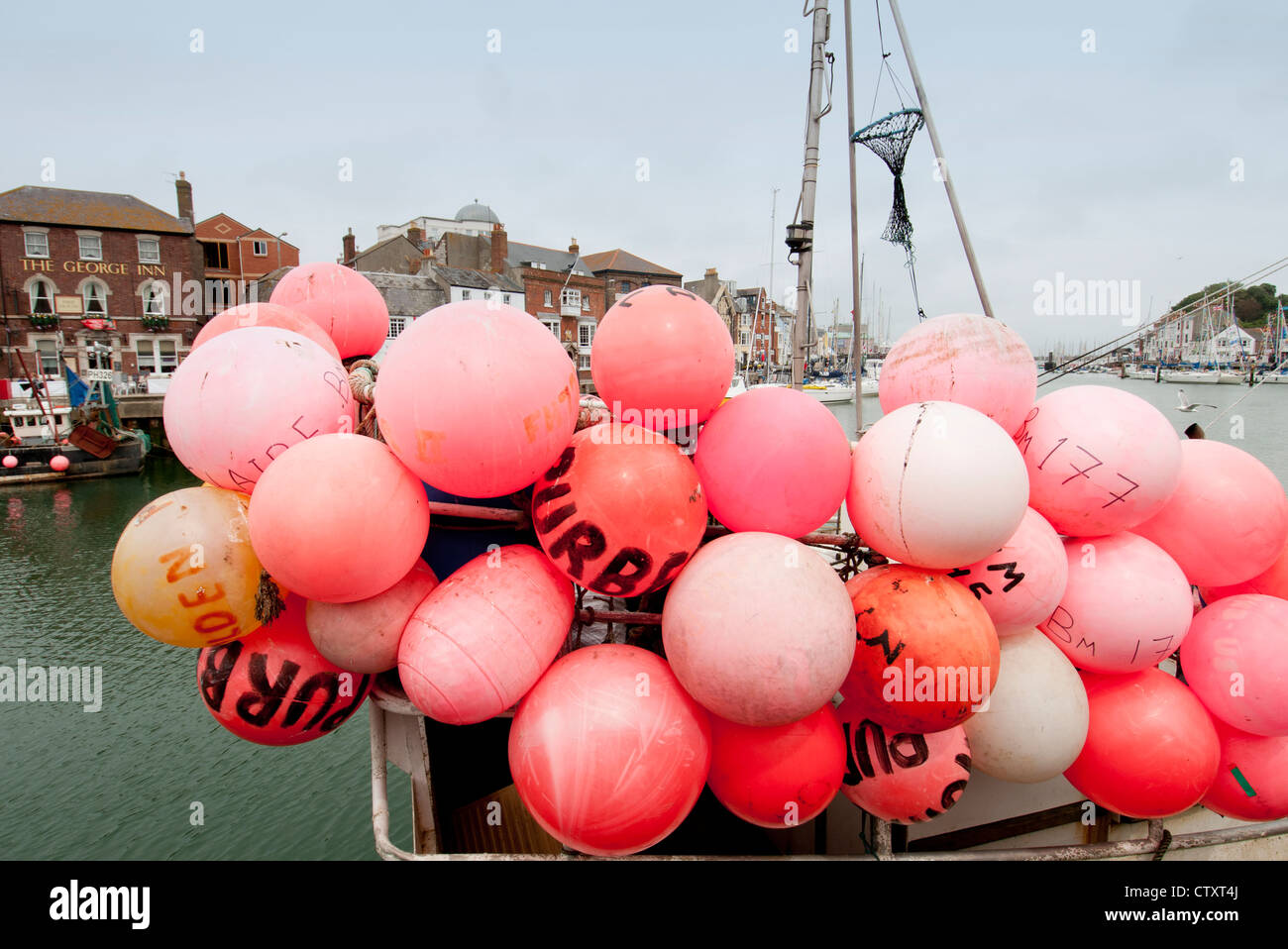 Orange boe su una barca da pesca nel porto di Weymouth Foto Stock