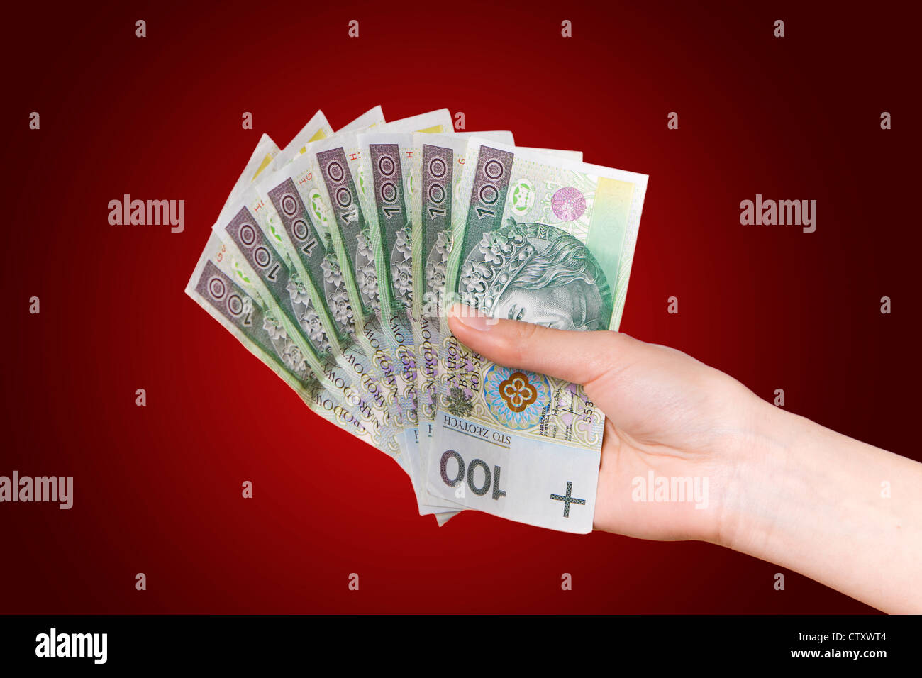 La mano con il polacco soldi su sfondo rosso Foto Stock