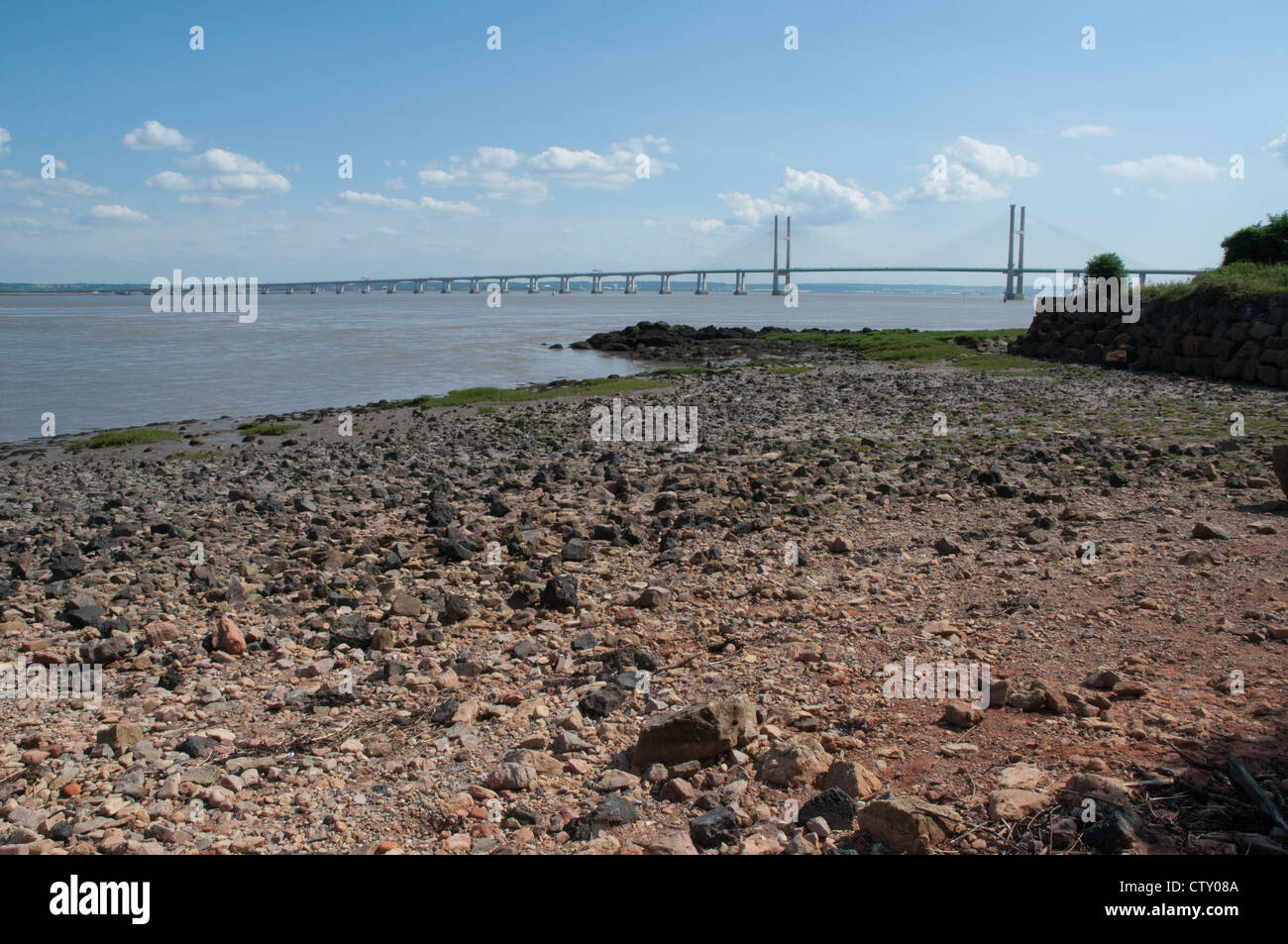 Rive del fiume Severn con rocce e spiaggia di ciottoli e seconda severn crossing in background Foto Stock