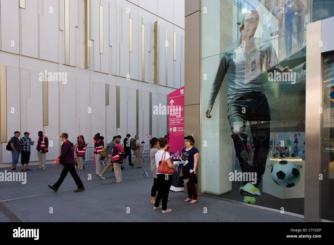 Con un gigante di David Beckham svettante su di esse per il Westfield Mall, spettatori pausa prima di entrare nel Parco Olimpico durante le Olimpiadi di Londra 2012, la trentesima Olimpiade. Si trova sulla frangia del 2012 Olympic Park, Westfield è il più grande d'Europa urban shopping center fornendo il principale accesso al parco olimpico con una centrale di "strada" dando il 75% dei visitatori olimpici di accesso alla stadio principale in modo spazio di vendita. Foto Stock