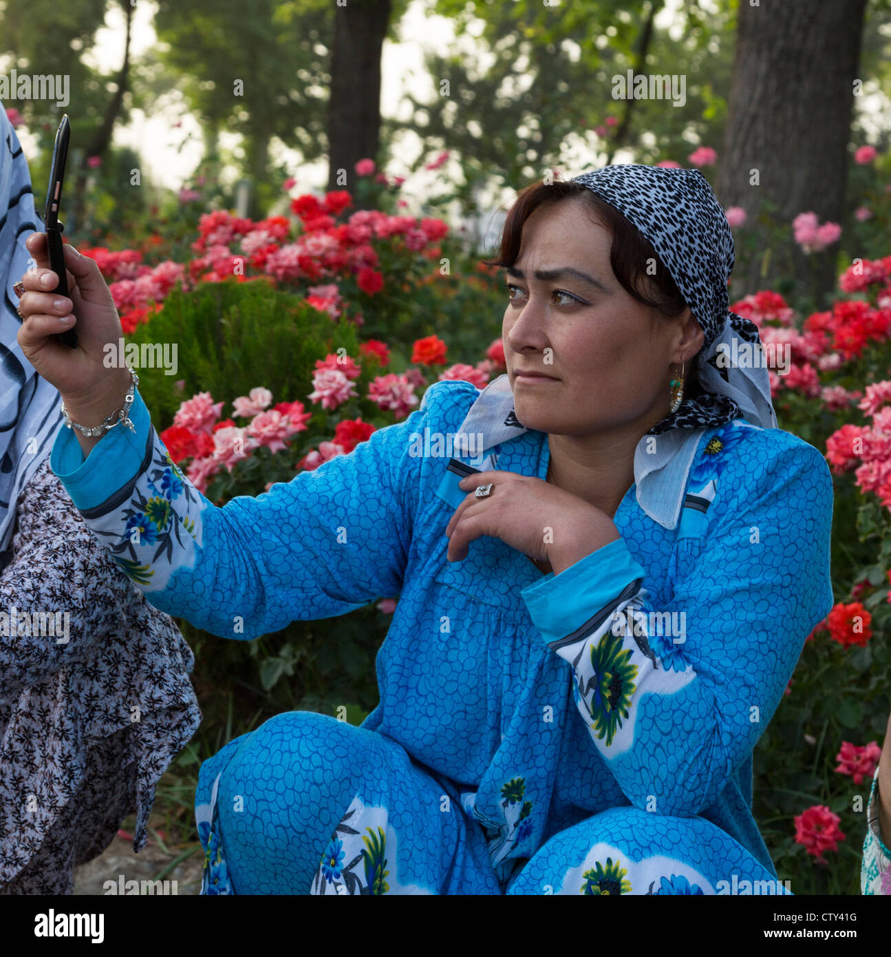 Donna tagiko iooking a schermo del telefono cellulare, Central Park, Dushanbe, Tagikistan Foto Stock