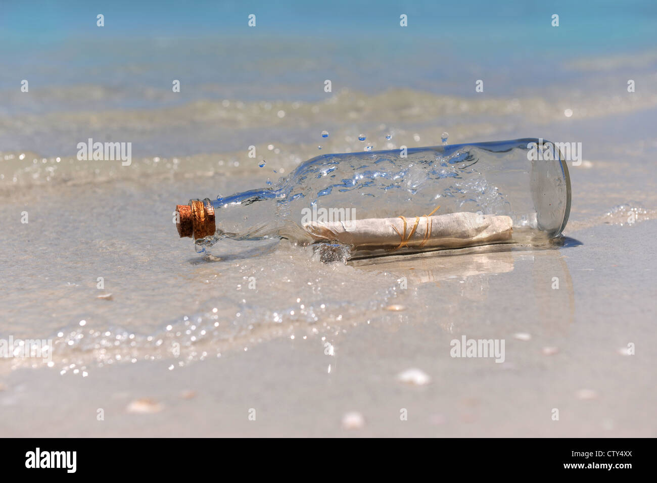 Un messaggio in bottiglia con onde che si infrangono sulla riva Foto Stock