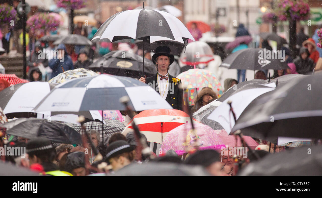 Wet Nychburris Guid in Dumfries. British estate meteo pioggia. L'uomo su palafitte con ombrellone in piedi sopra un mare di ombrelloni Foto Stock
