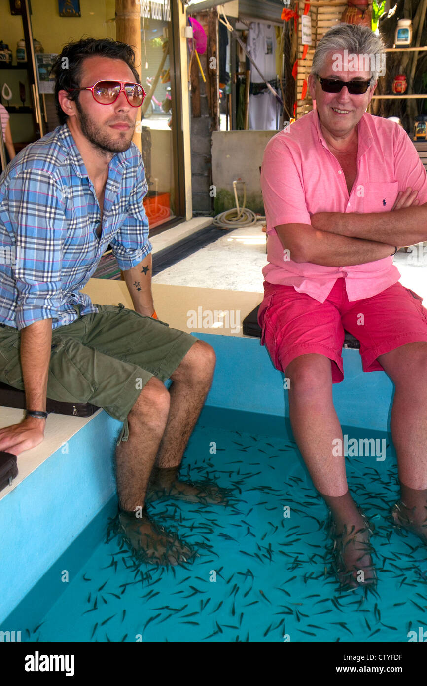 Gli uomini godono di un piede pedicure data dal doctor fish sull isola di Ko Samui, Thailandia. Foto Stock