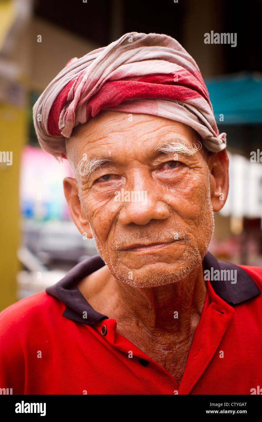 Guardare un buon vecchio vecchio uomo asiatico con turbante sulla testa, un triciclo il conducente in Kota bharu. Foto Stock