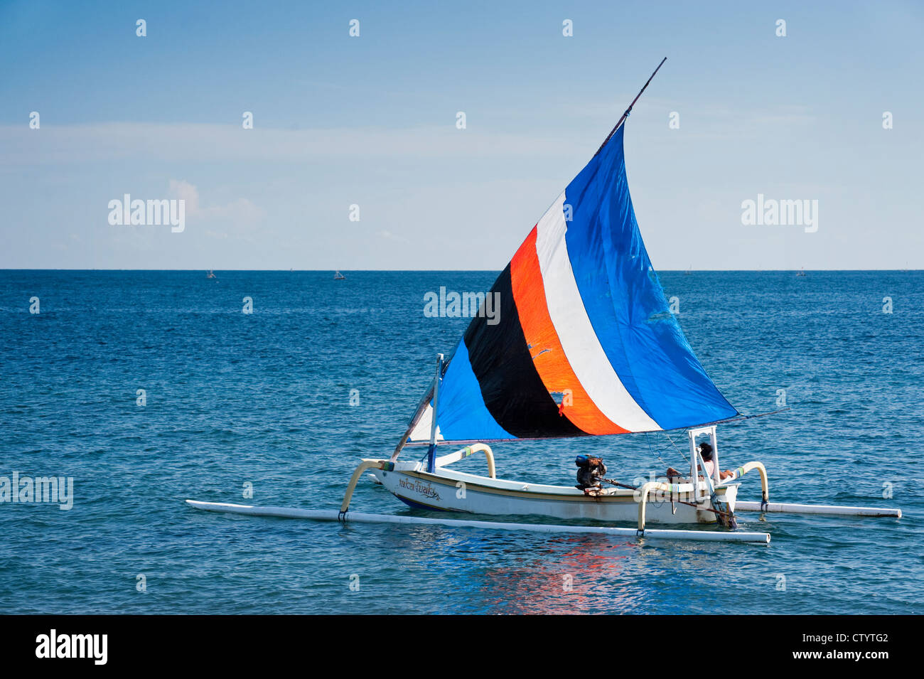 Un tradizionale design Balinese outrigger barca da pesca, chiamato jukung, vele lungo la Amed, costa di Bali in una bella giornata di sole. Foto Stock