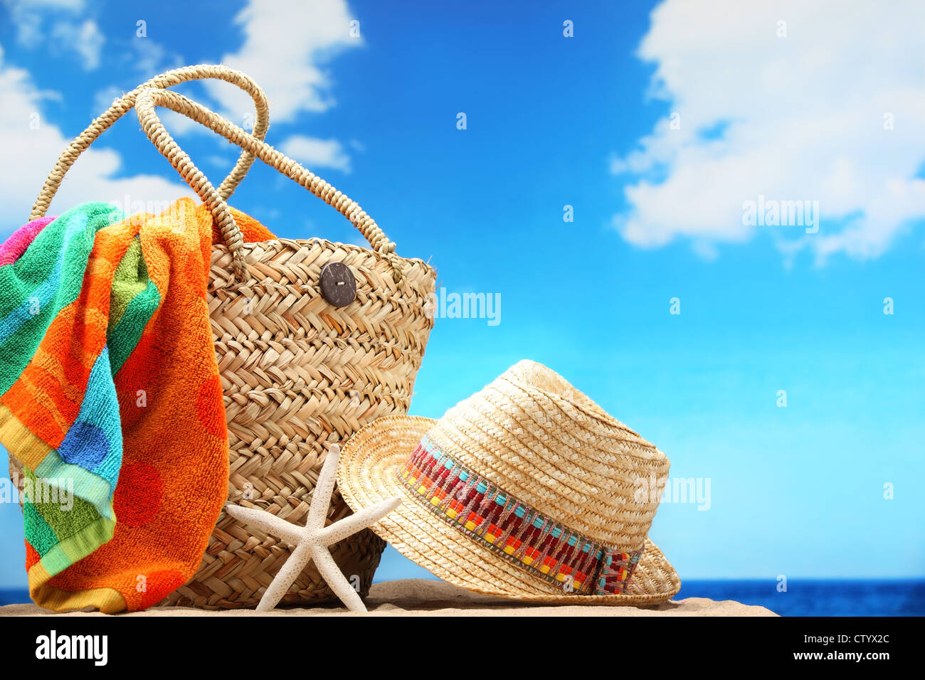 Primo piano della estate borsa da spiaggia e il cappello di paglia sulla spiaggia sabbiosa. Foto Stock