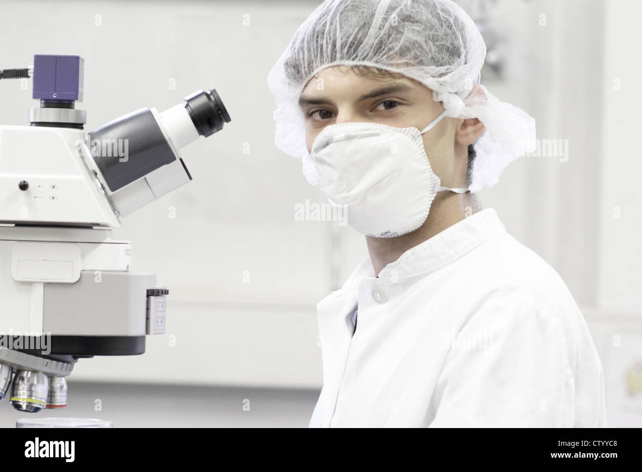 Scienziato permanente al microscopio in laboratorio Foto Stock