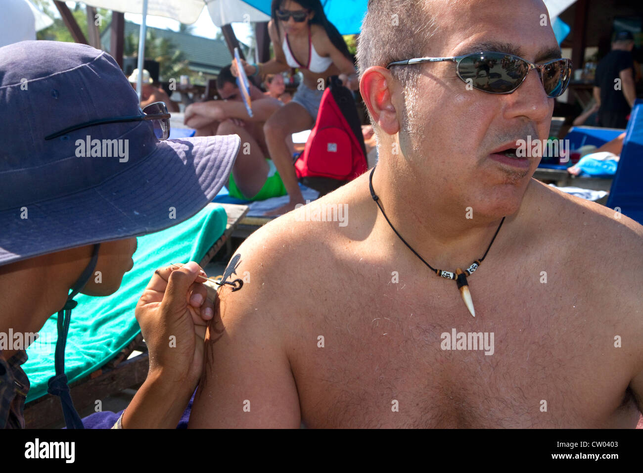 L'uomo riceve un tatuaggio tradizionale a Chaweng Beach sull'isola di Ko Samui, Thailandia. Foto Stock