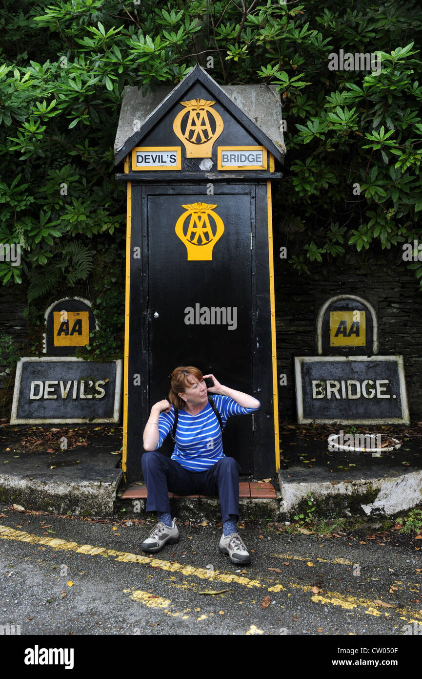 Donna che utilizza il telefono cellulare accanto a AA casella telefono Ponte del Diavolo Wales UK Foto Stock