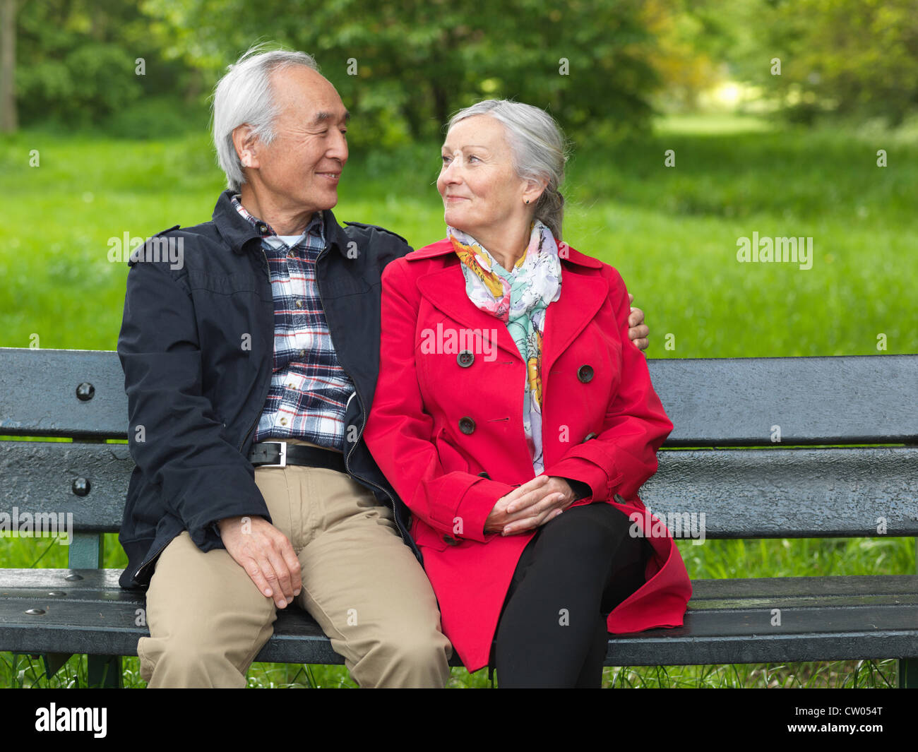 Coppia di anziani seduti su una panchina nel parco Foto Stock