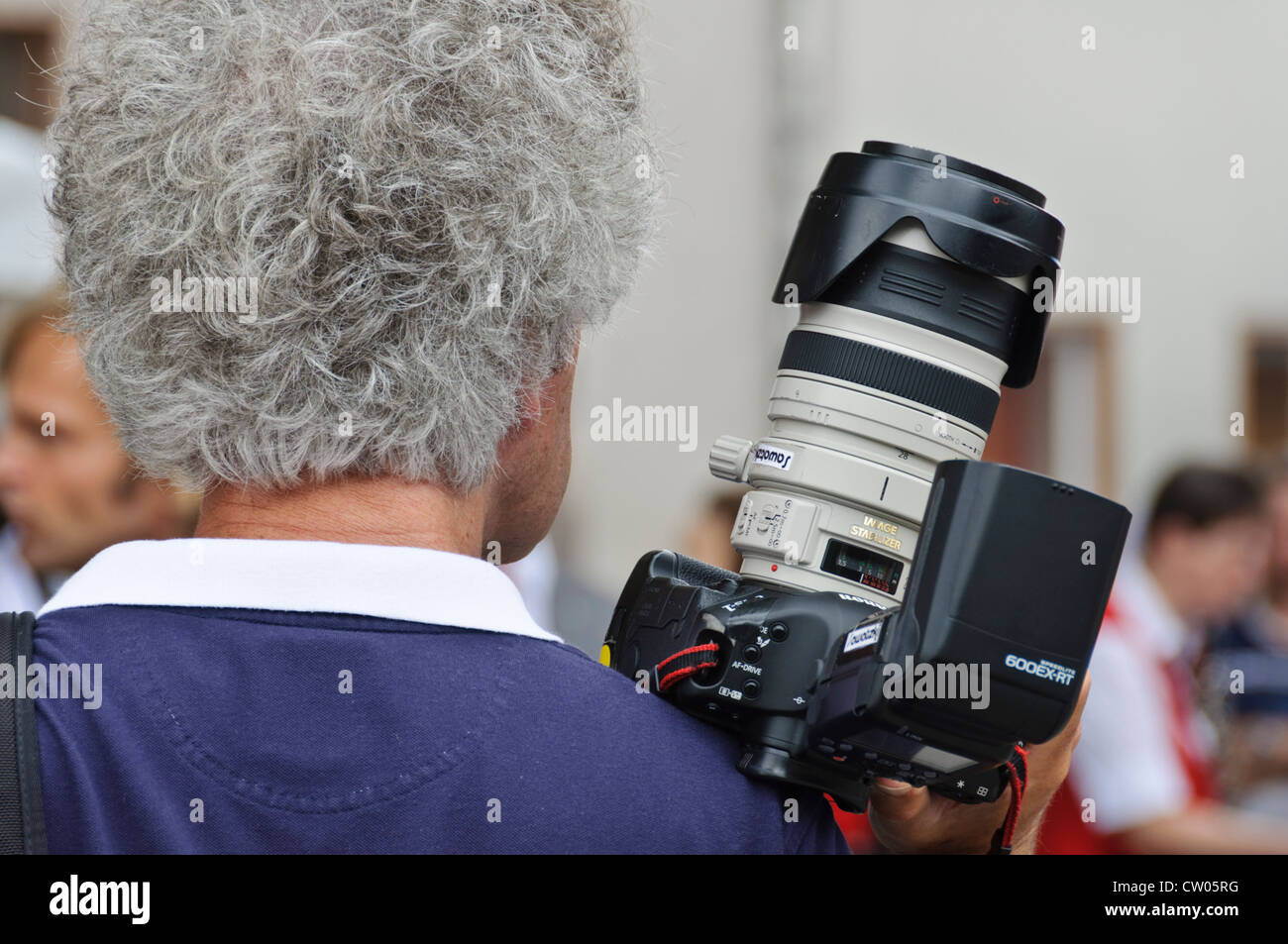Adulto uomo caucasico con il grigio capelli ricci, maschio professionale fotografo, prendendo le immagini con un frame completo Canon DSLR Foto Stock