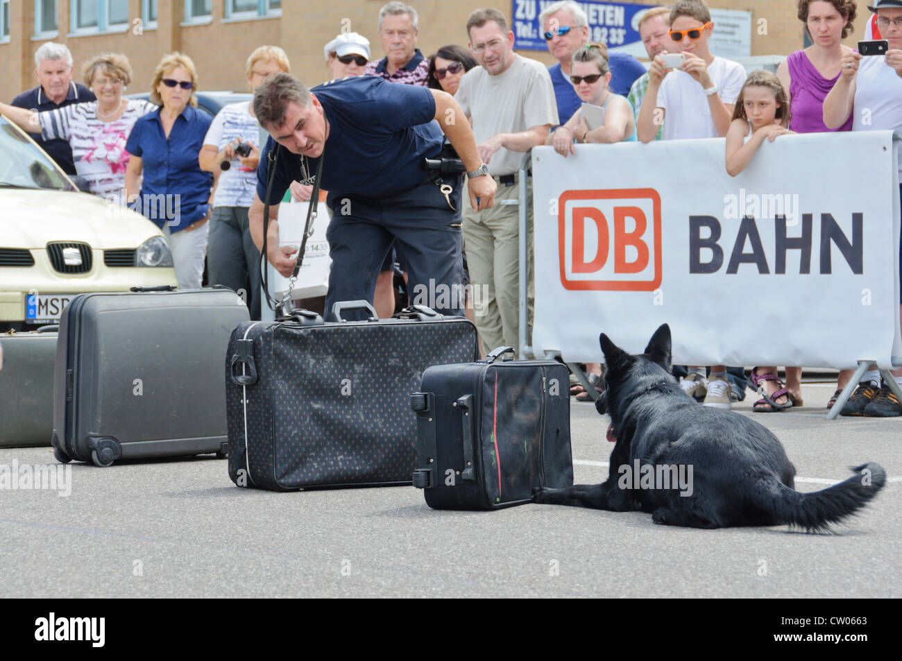 Sniffer di farmaco cane da un poliziotto tedesco K-9 unità di farmaco ricerca valigie per le droghe illegali guardato da spettatori, DB Deutsche Bahn Foto Stock