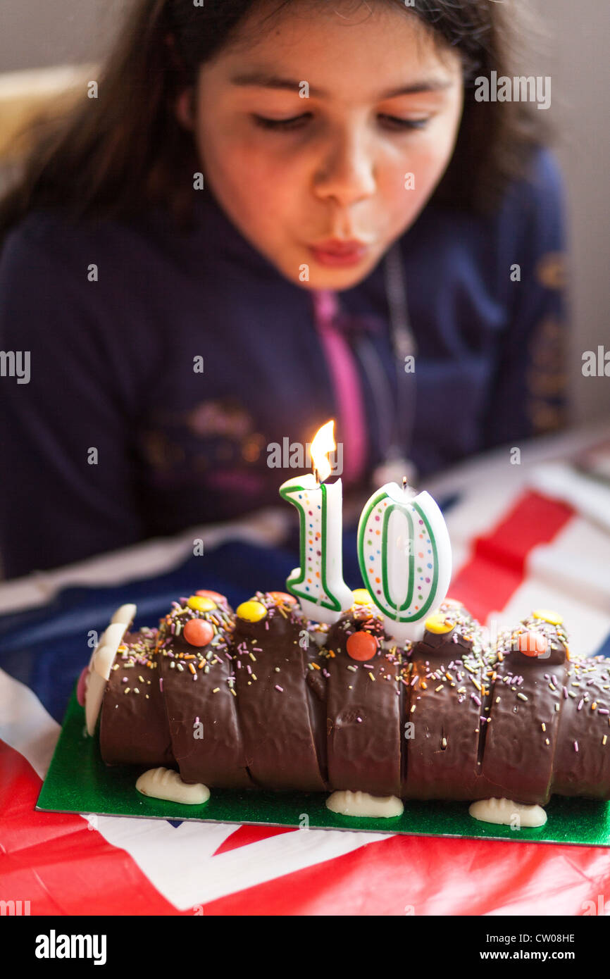 Dieci anni di old girl, soffiando le candeline sulla sua torta di compleanno. Foto Stock