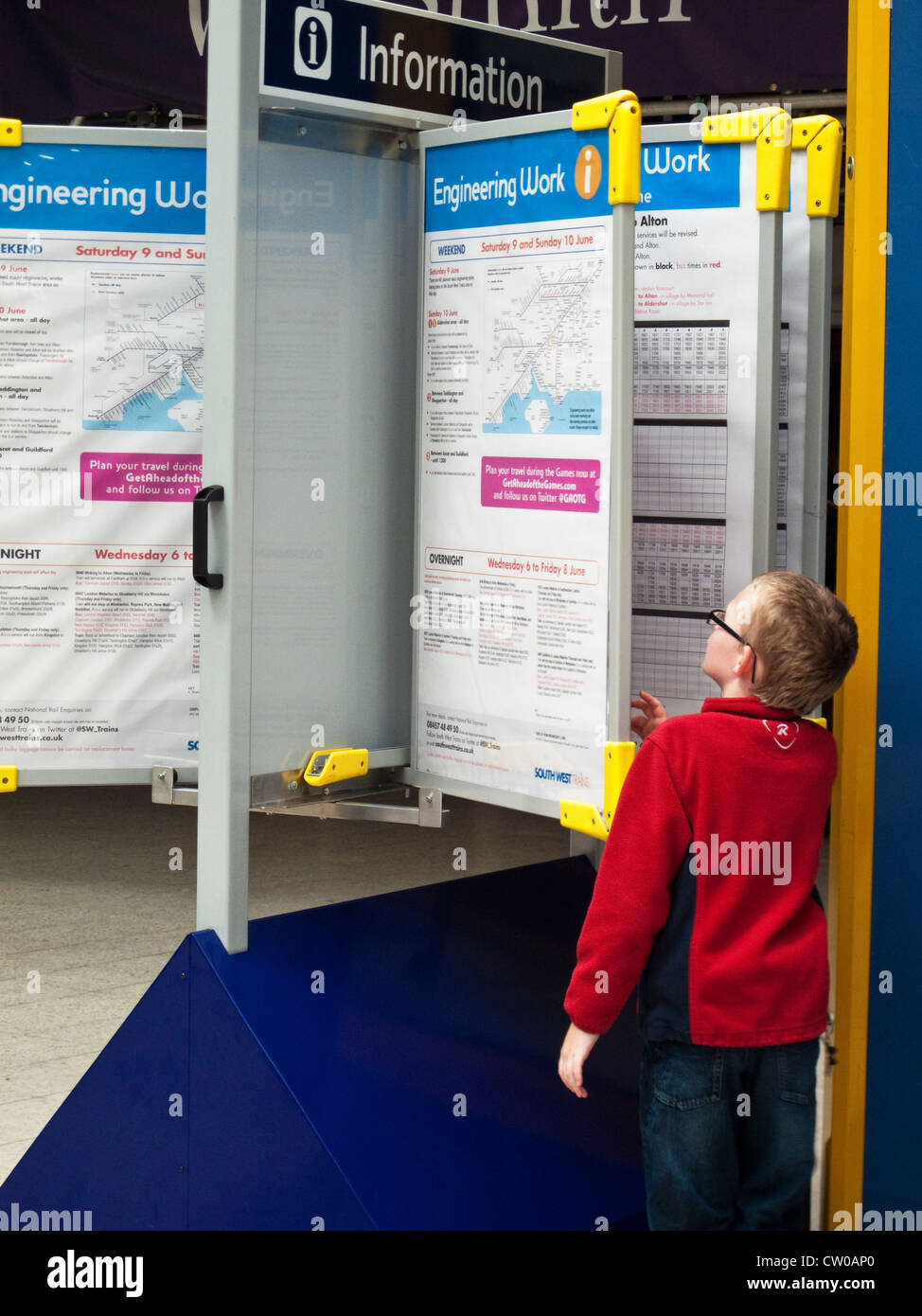 Un ragazzo guardando gli orari dei treni presso la stazione di Waterloo London REGNO UNITO Foto Stock