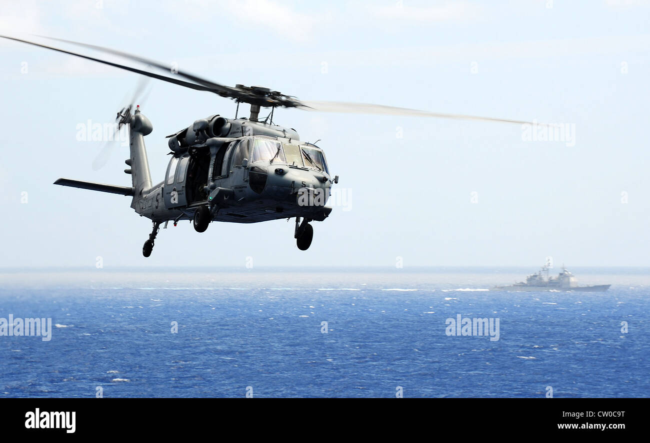 Un MH-60s seahawk elicottero assegnato al golden falchi di elicottero di mare squadrone di combattimento (HSC) 12 vola oltre il ticonderoga-class guidato-missili cruiser uss capo st. george (CG 71) durante un aria di dimostrazione di potenza al di sopra della nimitz-class portaerei USS Abraham Lincoln (CVN 72). Lincoln è in rotta verso gli Stati Uniti per completare otto mesi di cambiamento di installazione di homeport durante il quale esso ha operato negli Stati Uniti 5th, sesto e settimo flotta aree di responsabilità. Foto Stock Un MH-60s seahawk elicottero assegnato al golden falchi di elicottero di mare squadrone di combattimento (HSC) 12 vola oltre il ticonderoga-class guidato-missili cruiser uss capo st. george (CG 71) durante un aria di dimostrazione di potenza al di sopra della nimitz-class portaerei USS Abraham Lincoln (CVN 72). Lincoln è in rotta verso gli Stati Uniti per completare otto mesi di cambiamento di installazione di homeport durante il quale esso ha operato negli Stati Uniti 5th, sesto e settimo flotta aree di responsabilità. Foto Stock