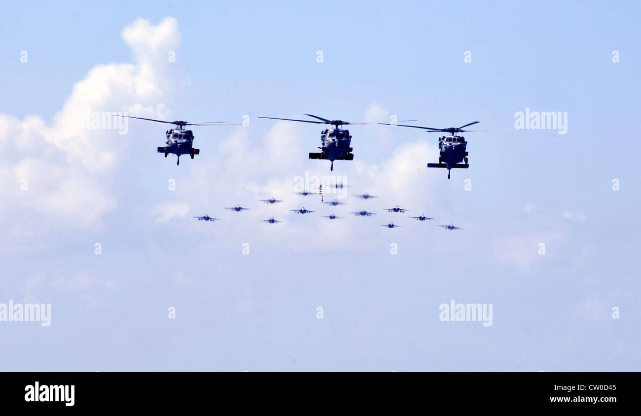 MH-60S gli elicotteri Seahawk assegnati ai Falconi d'oro dello Squadrone di combattimento di Mare dell'elicottero (HSC) 12 volano davanti ad una formazione di F/A-18 Hornets e Super Hornets assegnati alla Carrier Air Wing (CVW) 2 sopra la compagnia aerea di classe Nimitz USS Abraham Lincoln (CVN 72) durante una dimostrazione di potenza aerea. Lincoln sta ritornando negli Stati Uniti dopo il completamento di un cambio di otto mesi di distribuzione di homeport durante il quale operò nelle aree di responsabilità della flotta degli Stati Uniti 5, 6 e 7. Foto Stock