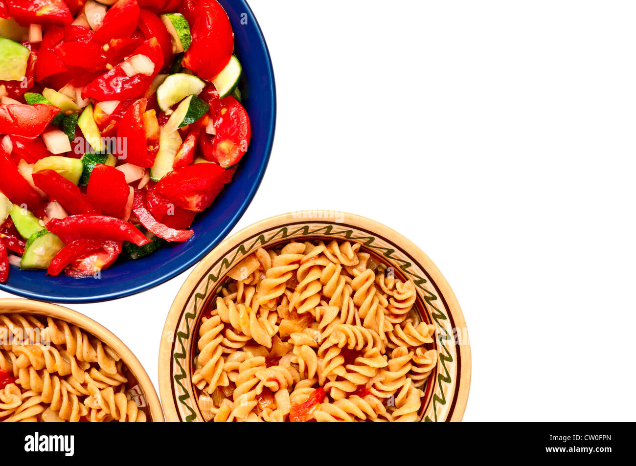 Una ciotola di insalata e due piastre con pasta con pomodori, isolati su sfondo bianco Foto Stock