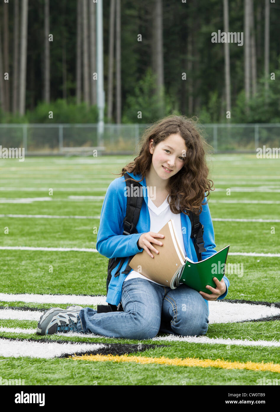 Ragazza giovane lo studio sul campo di calcio con boschi in background Foto Stock