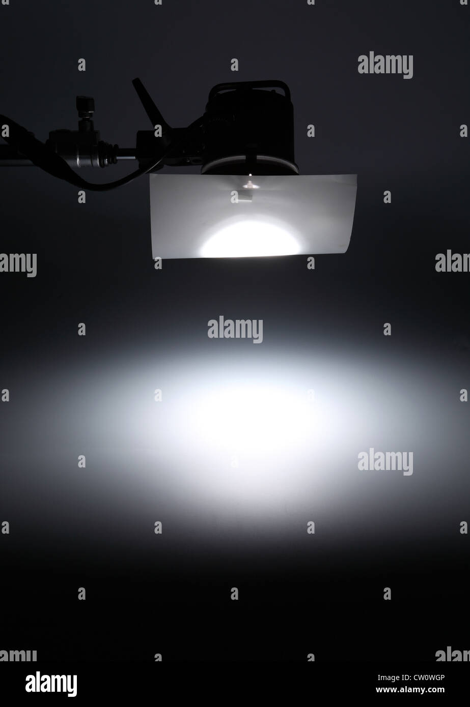 Una luce fotografici da sopra la creazione di un faretto bianco su un vuoto di sfondo scuro. Foto Stock