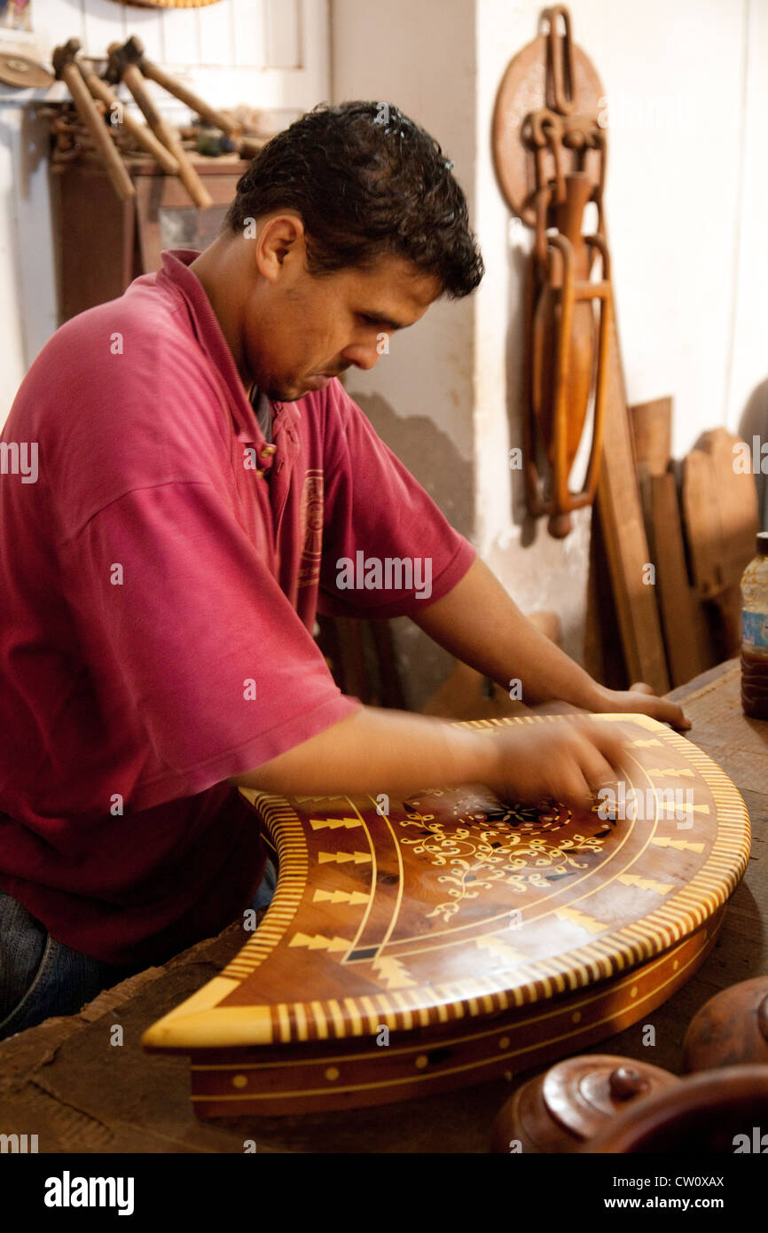Un marocchino artigiano rendendo un legno intarsiato tavolo, Essaouira, Marocco Foto Stock