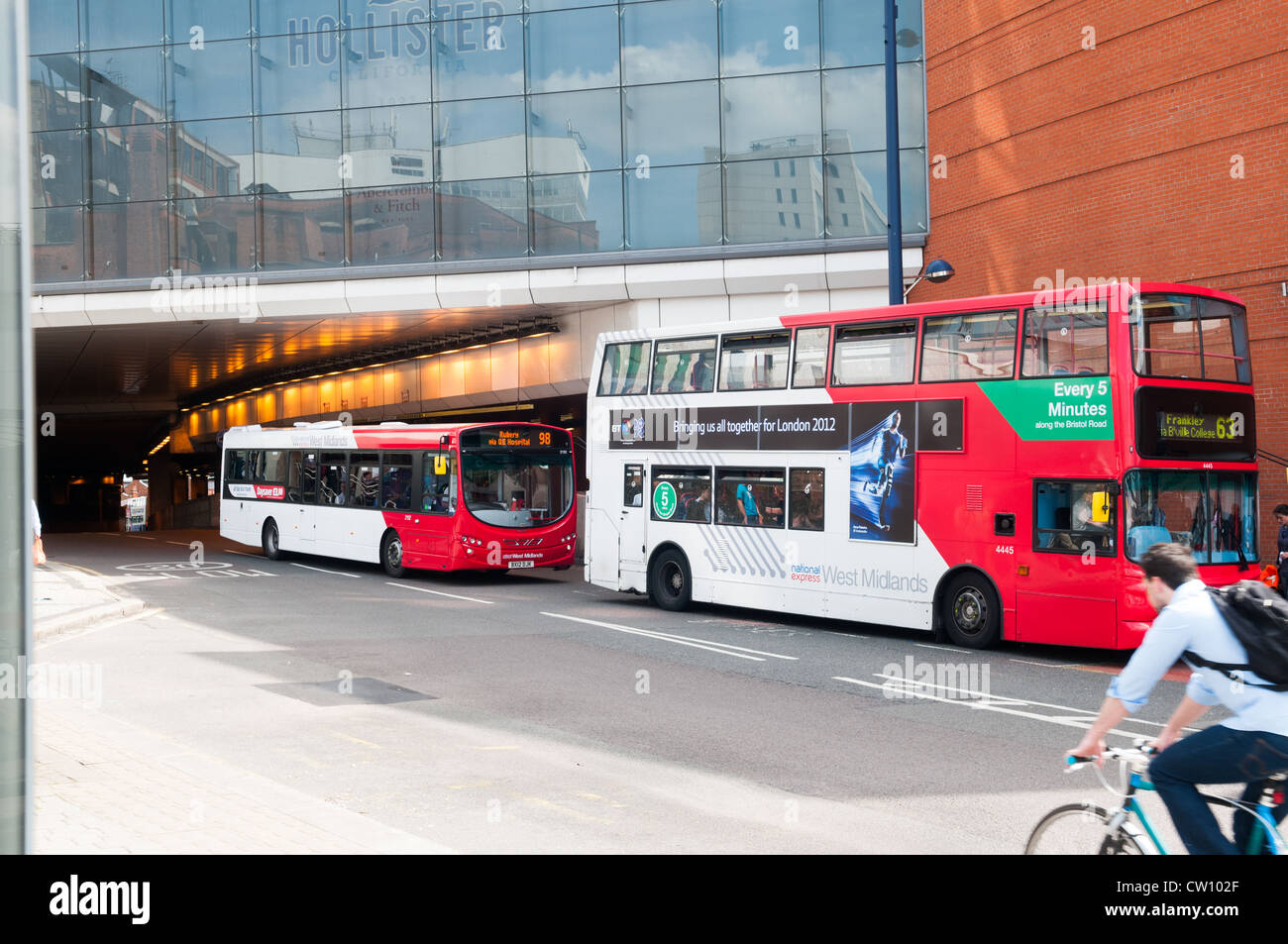 Due autobus parcheggiato fuori Birmingham New Street stazione ferroviaria con un ciclista che passa in primo piano Foto Stock