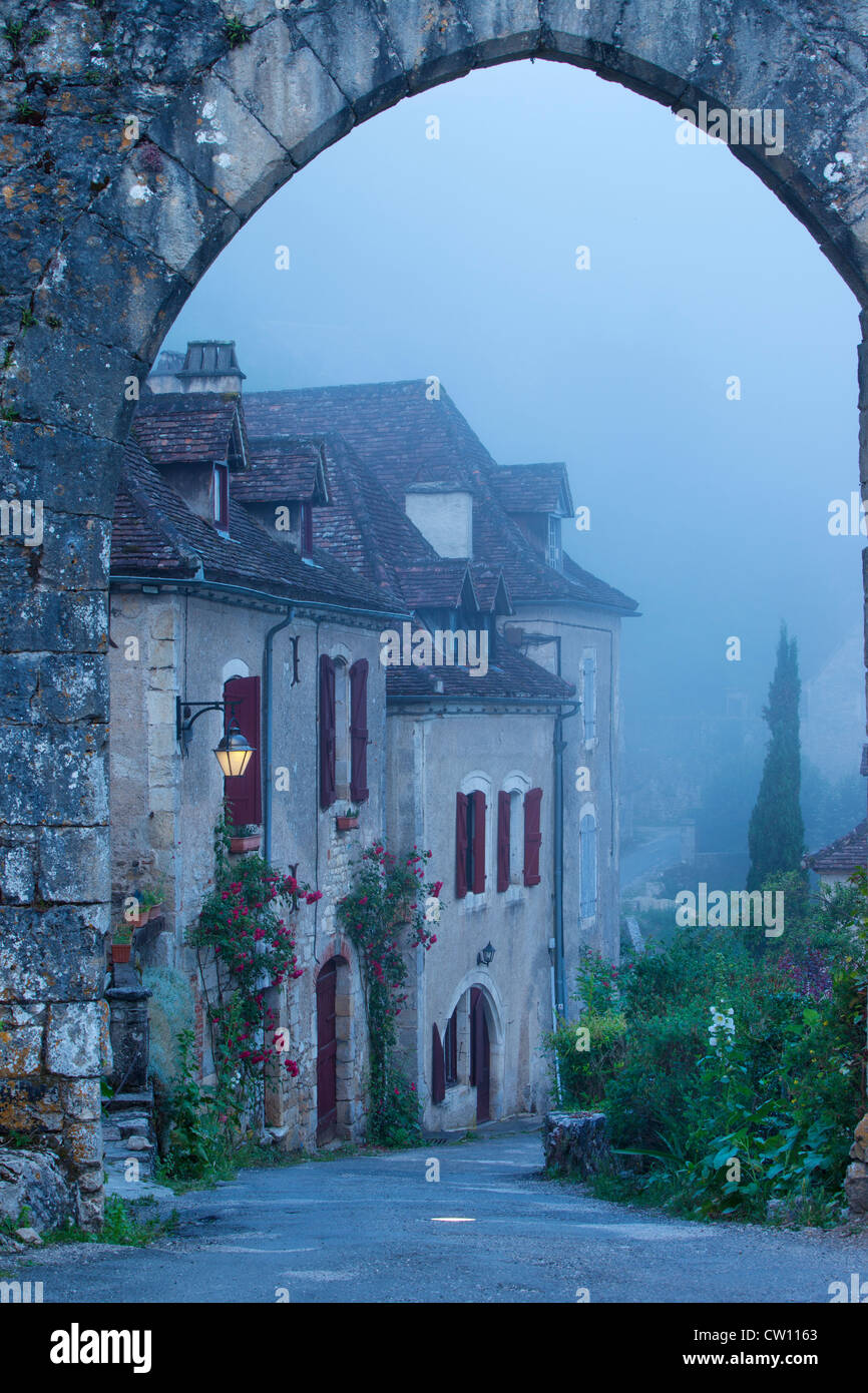 Misty dawn al varco di ingresso a Saint Cirq Lapopie, Valle del Lot, Midi-Pirenei, Francia Foto Stock
