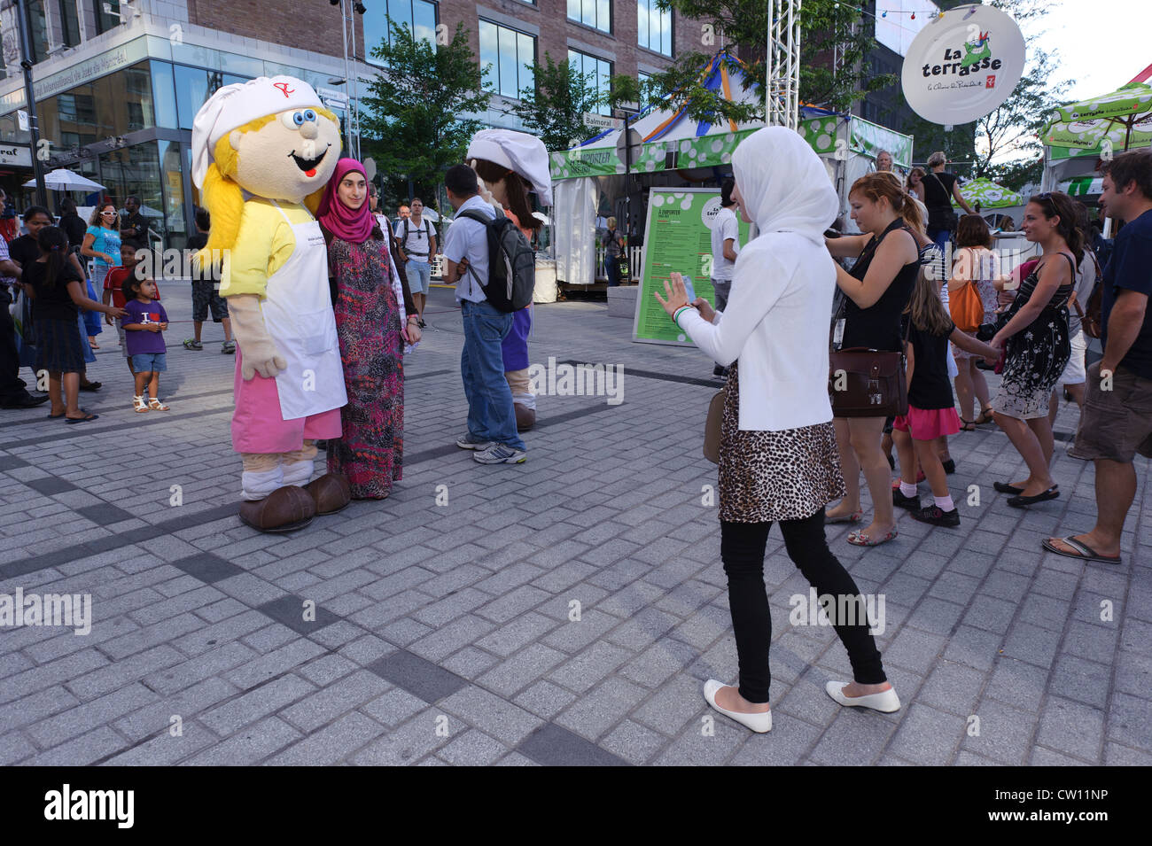 Giovane donna che indossa un velo di scattare una foto di un amico con una mascotte durante il Montreal solo per ride festival. Foto Stock