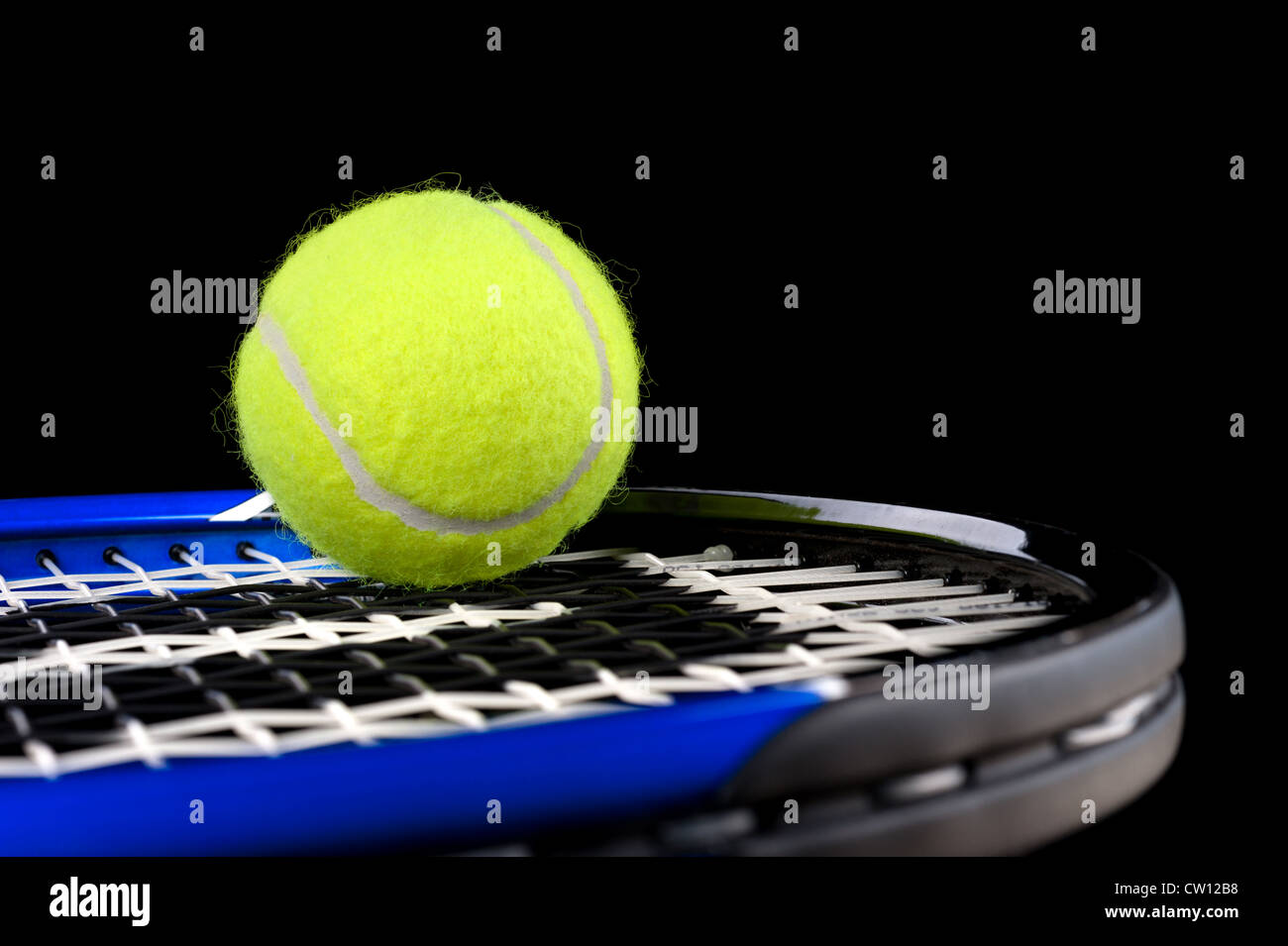 Un nuovo verde palla da tennis in appoggio sulla sommità di una racchetta blu con uno sfondo nero. Foto Stock