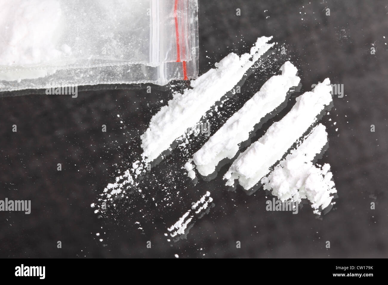 La cocaina in polvere in linee e il pacchetto sullo specchio, primo piano Foto Stock