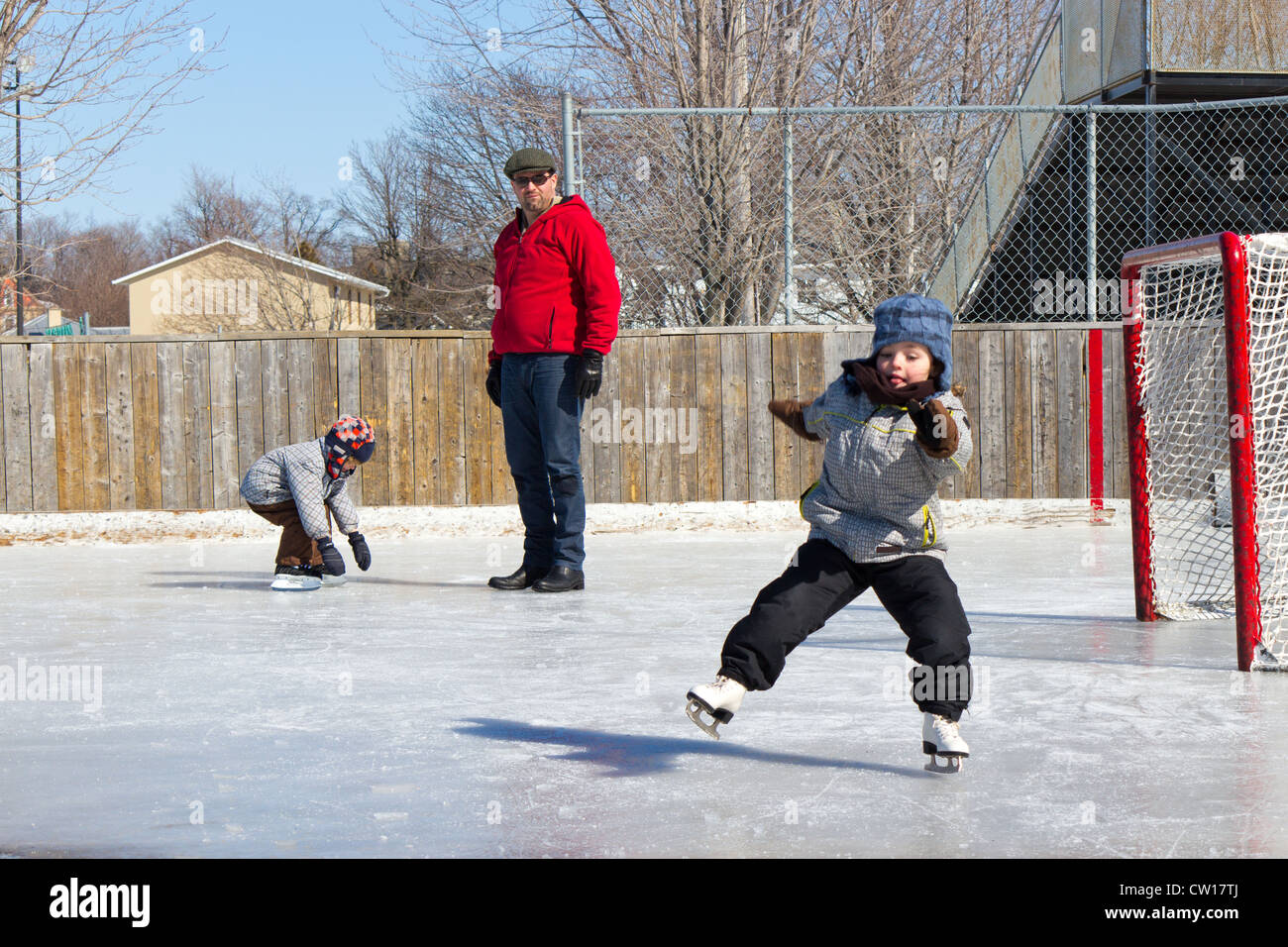 Padre con il figlio e la figlia a giocare presso la pista da pattinaggio su ghiaccio in inverno. Foto Stock
