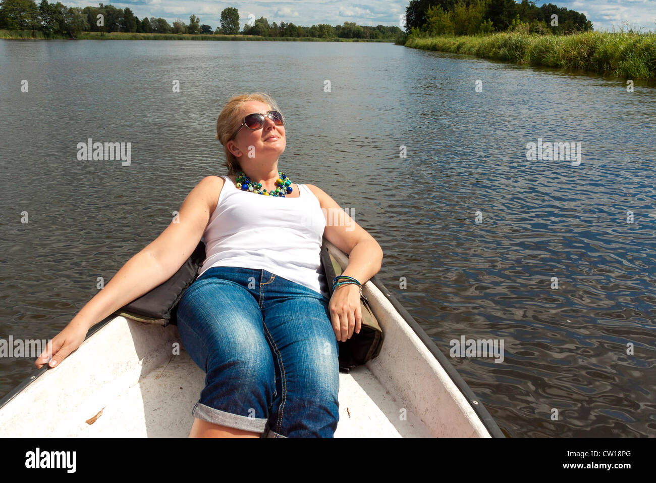 Donna di riposo in barca da pesca sul fiume Narew, Polonia Foto Stock