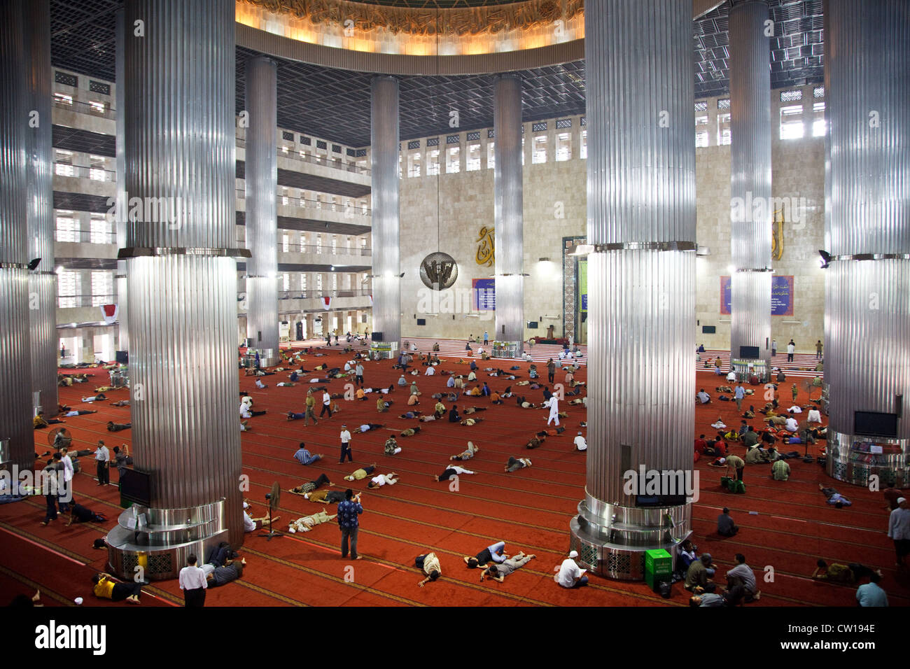 La gente la posa sul pavimento dopo la preghiera alla Moschea Istiqlal a Jakarta, Indonesia Foto Stock