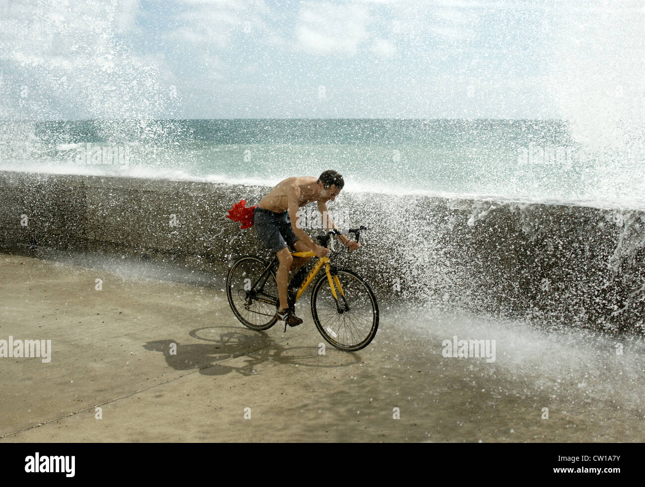 Ciclista nel mezzo dell'onda splash a Brighton Foto Stock