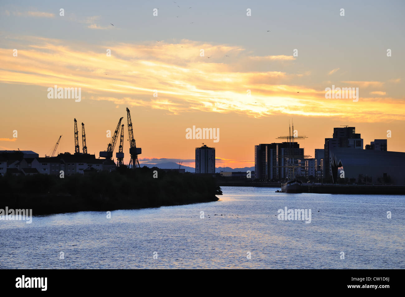 Impostazione sun fornisce un cielo arancione su una città scozzese skyline visto da Bell's Bridge Glasgow, UK. Foto Stock