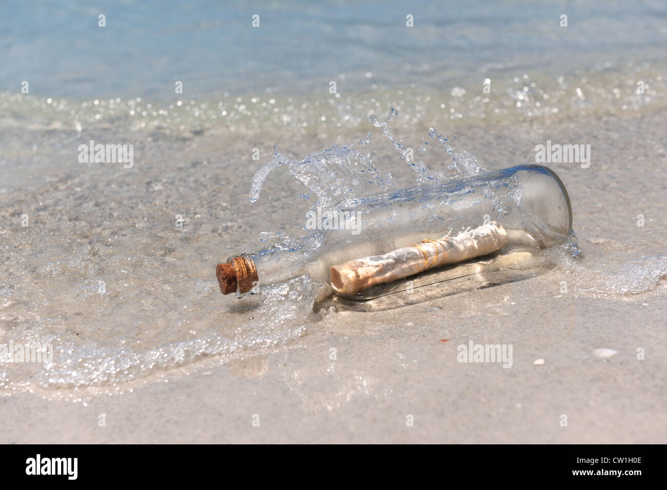 Spruzzi delle onde su un messaggio in bottiglia recante sulla riva Foto Stock
