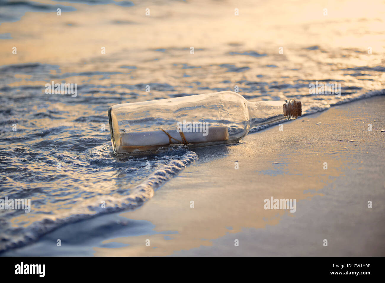 Un messaggio in bottiglia sulla spiaggia durante il tramonto Foto Stock