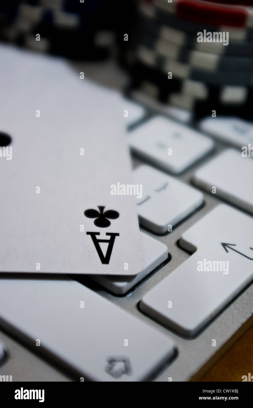 Un asso del club la riproduzione di carta in cima a una tastiera con poker chips in background. Foto Stock