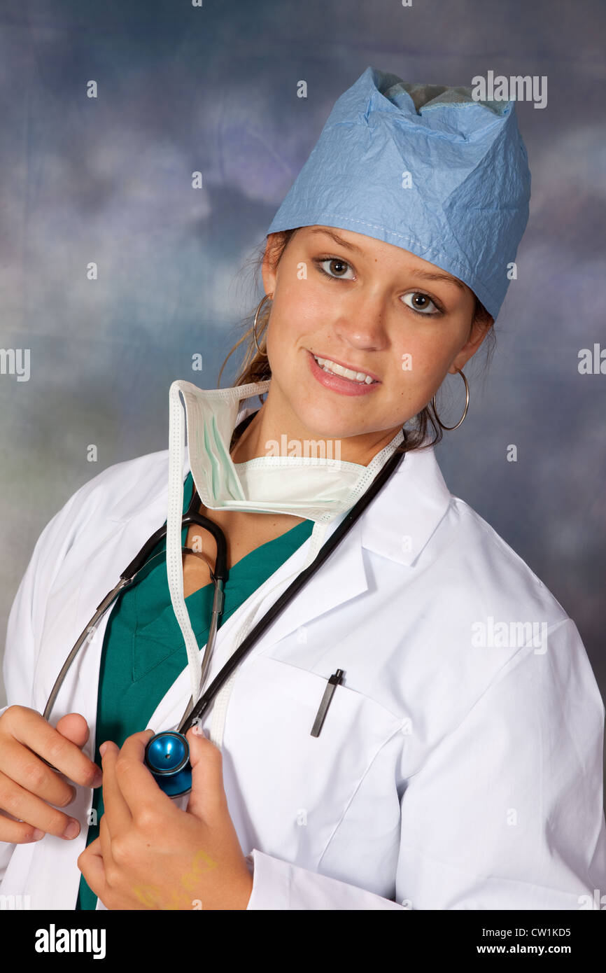 Donna operatore sanitario, medico o infermiere con camice, lo stetoscopio e il cappuccio chirurgico con maschera, guardando la telecamera Foto Stock