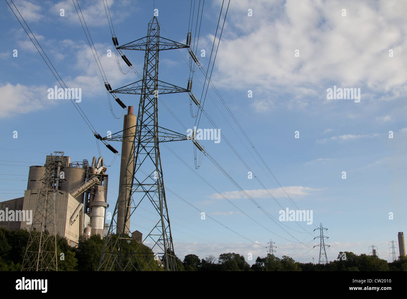 Enorme energia elettrica tralicci che trasportano la corrente dalla potenza di Aberthaw stazione passano davanti al Aberthaw opere in cemento Foto Stock