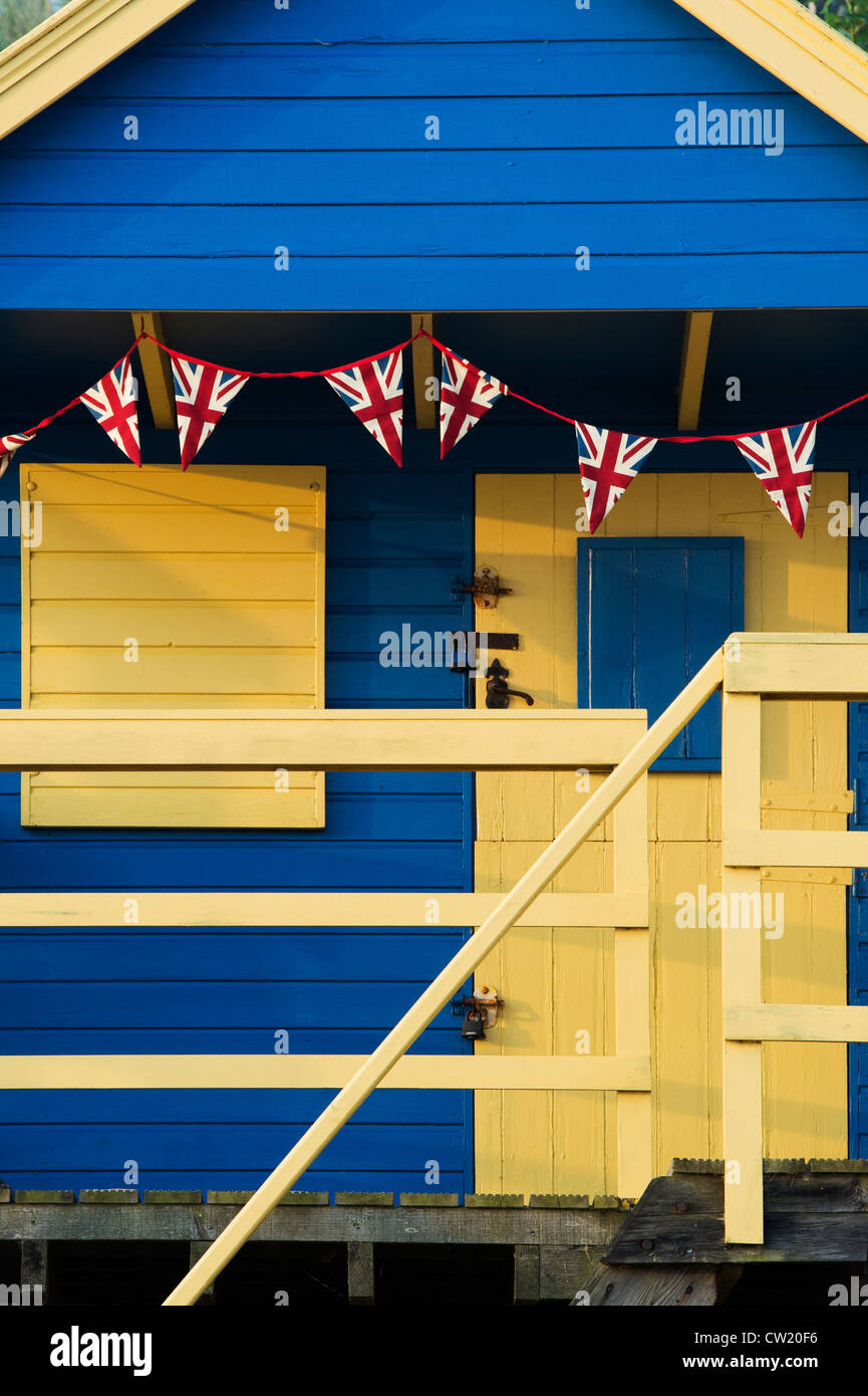 Union Jack flag bunting su una pittoresca spiaggia di capanna. Pozzetti accanto al mare. Norfolk, Inghilterra Foto Stock