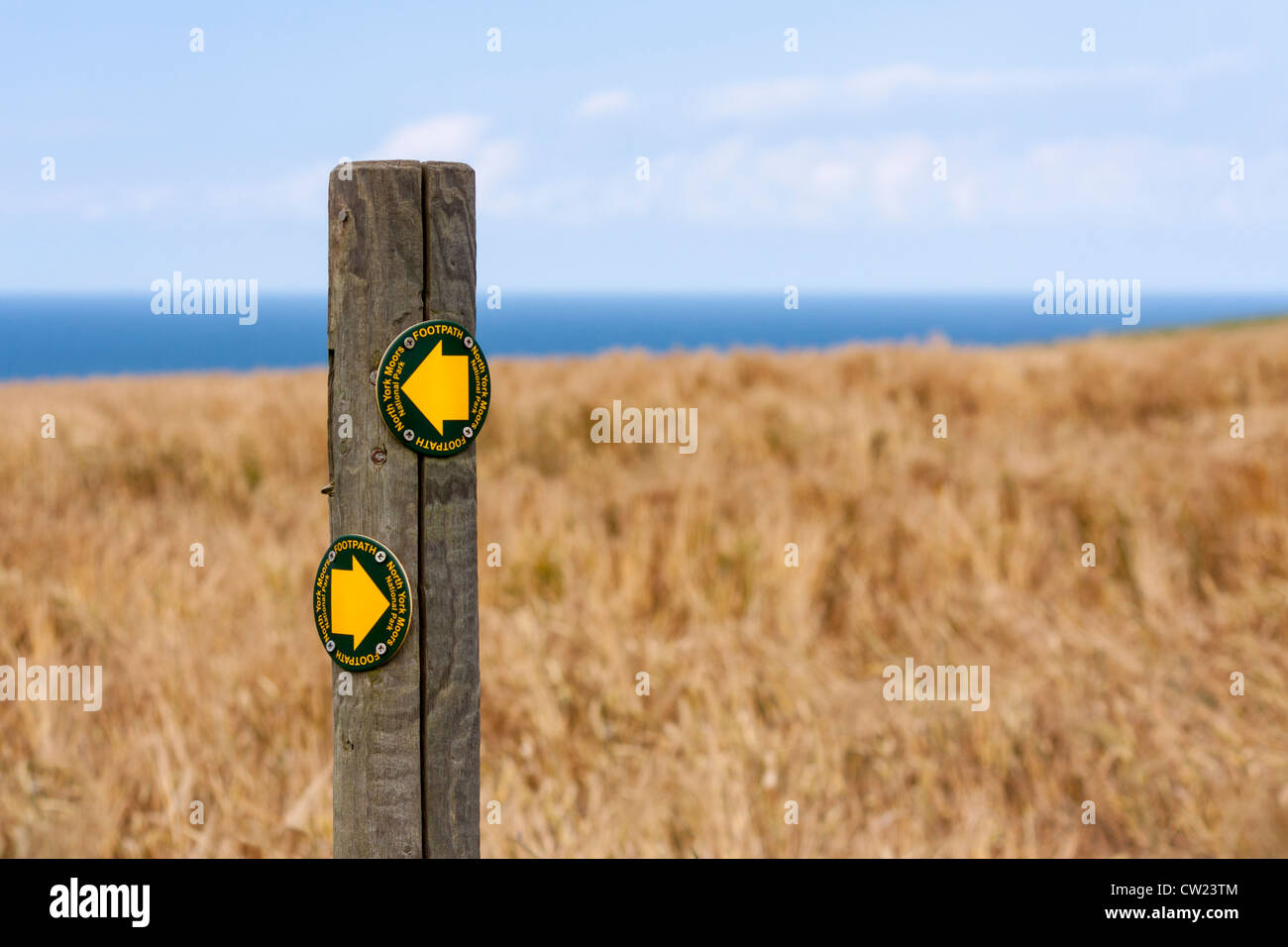 Un North Yorkshire Parco Nazionale sentiero segno con una vista di un campo di mais e di mare in background. Foto Stock