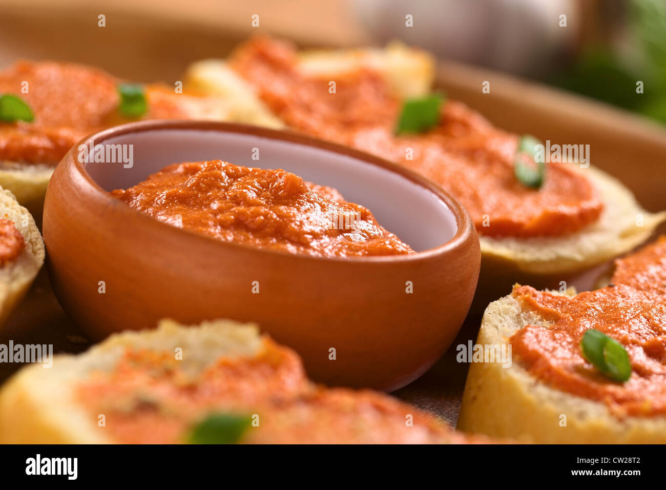 Freschi Fatti in casa pomodoro-diffusione di burro in una piccola ciotola con crostini sul piatto di legno Foto Stock