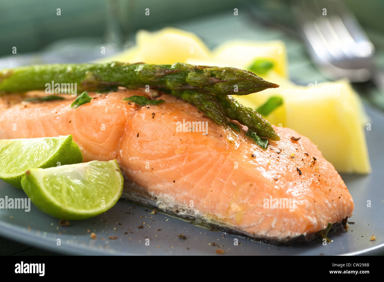 Cotto al forno filetto di salmone con asparagi verdi, spicchi di lime e patate bollite Foto Stock