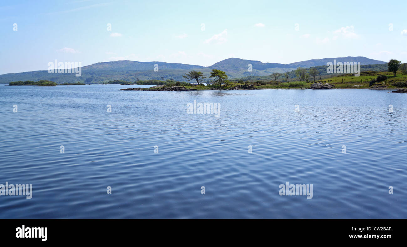 Vecchia barca con una strana ancoraggio, in un tranquillo lago in IrelandA calmo lago circondato da verdi colline Foto Stock