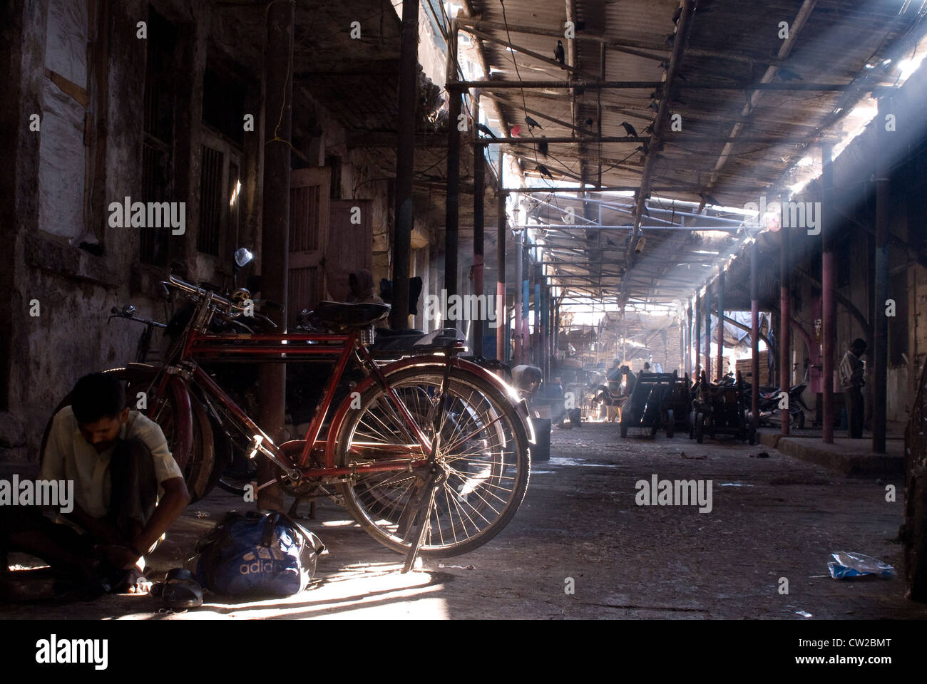 Operaio lavora con i suoi strumenti seduta accanto alla sua bicicletta - mercato Crawford, Mumbai - India Foto Stock