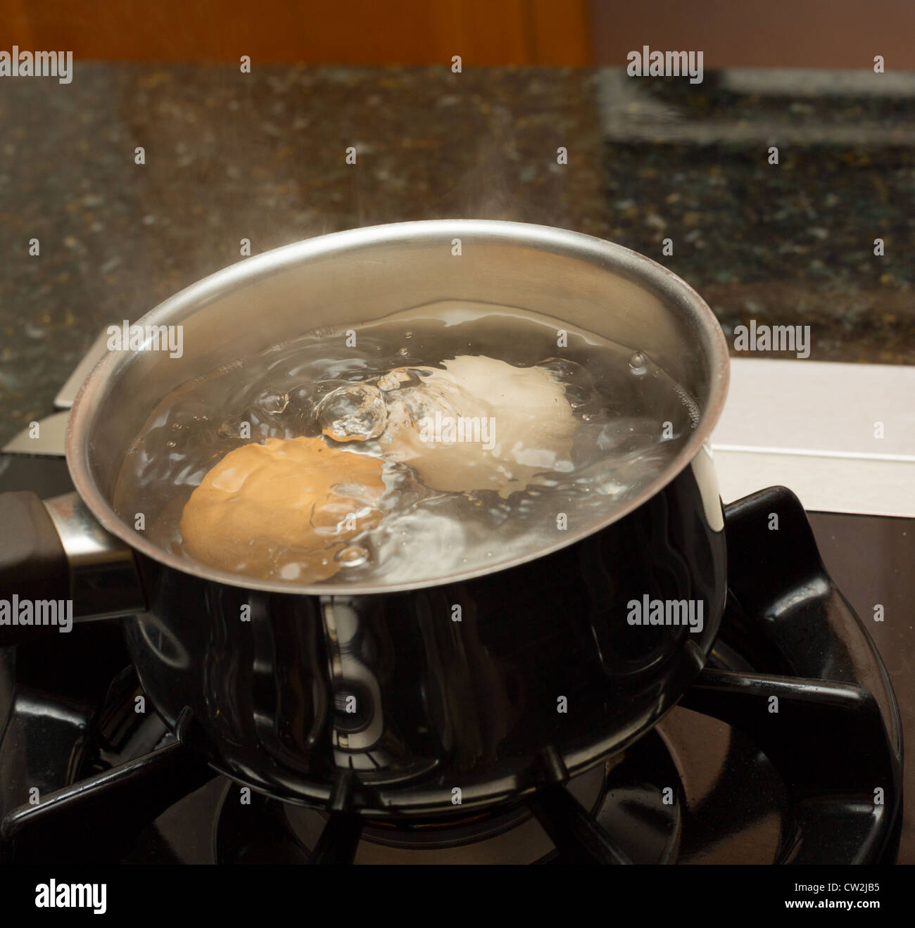 Acqua bollente in pentola di vetro trasparente sul piano cottura Foto stock  - Alamy