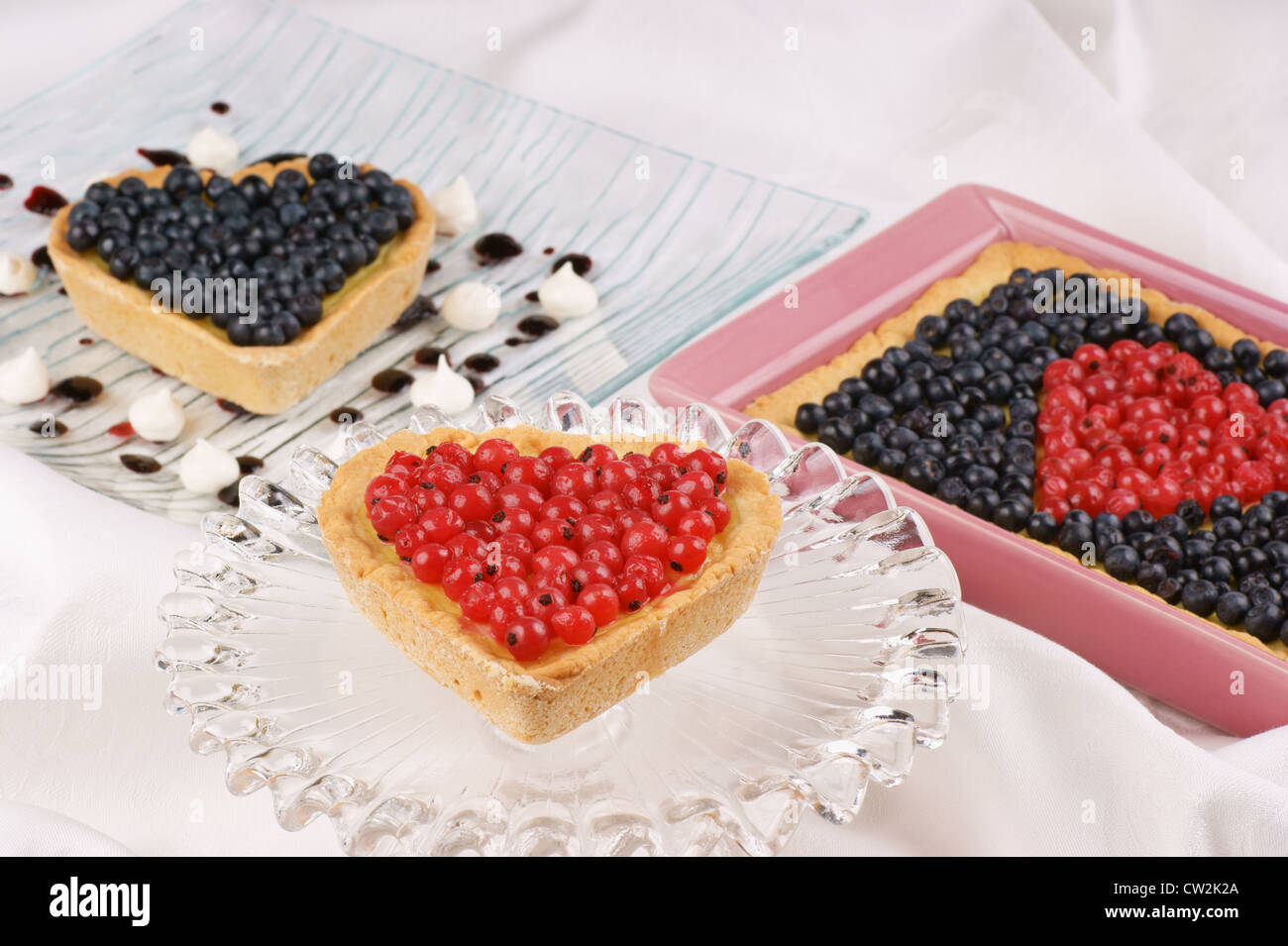 A forma di cuore crostata con i ribes rossi serviti sulla torta di vetro stand Foto Stock